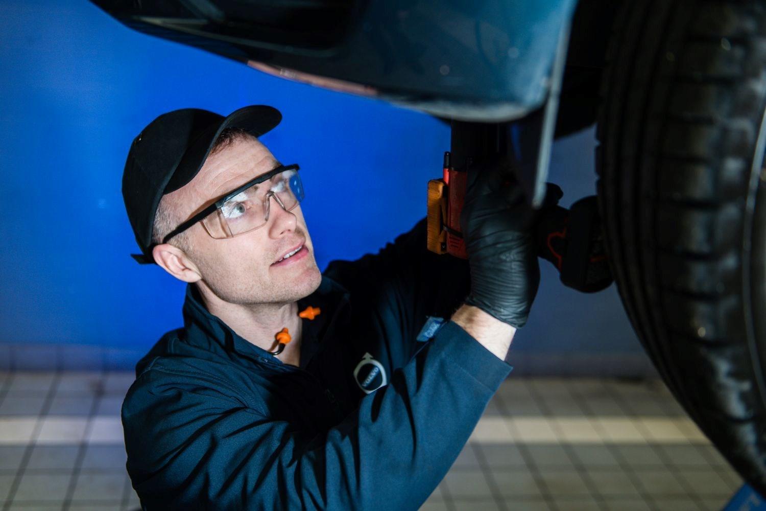Agnew Belfast Volvo engineer inspects used car with handheld light for damage to repair during Free Volvo Repair