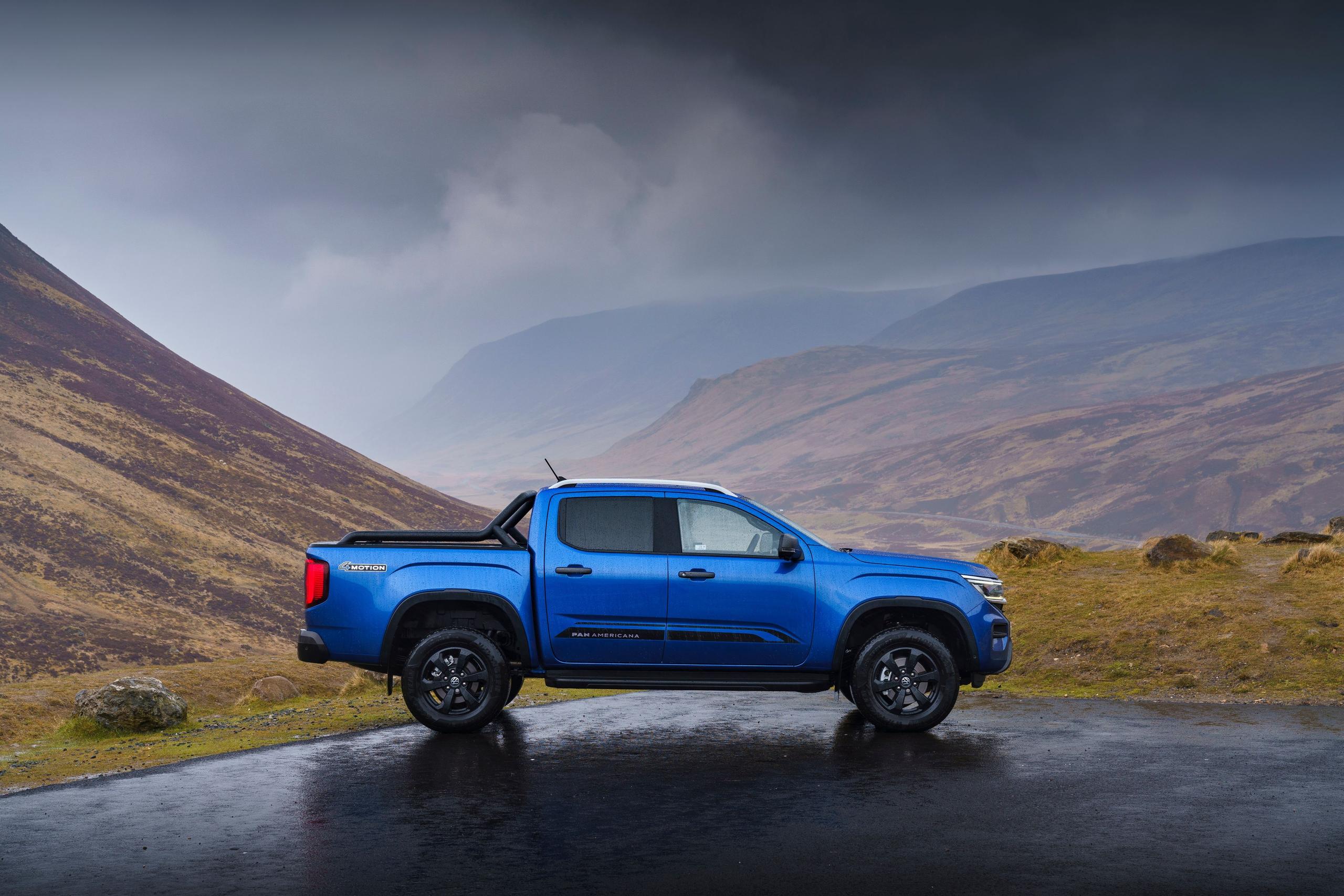 Side view of the new Volkswagen Amarok (PanAmericana trim), parked in countryside car park with mountains behind