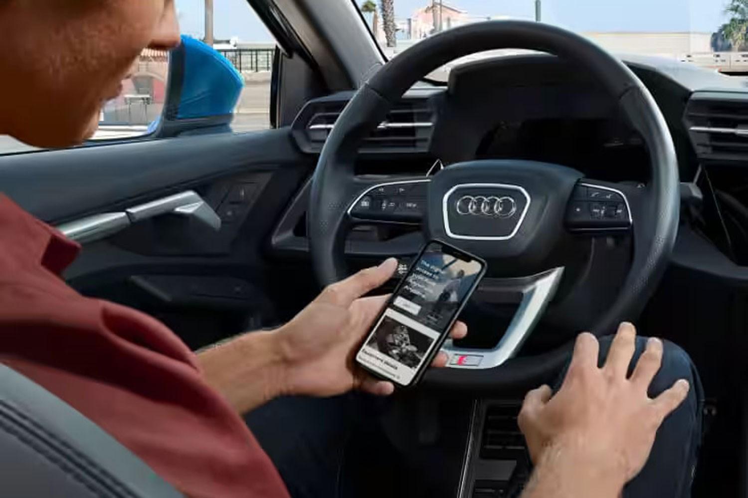 Image of Audi driver holding their smartphone using the Audi Plug and Play app