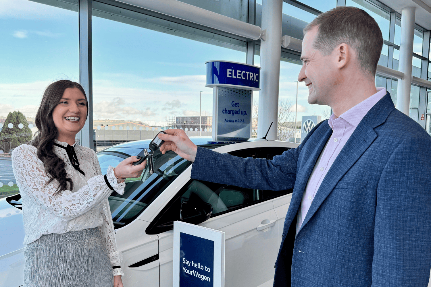 Volkswagen staff member handing the keys of a new car over to a customer.