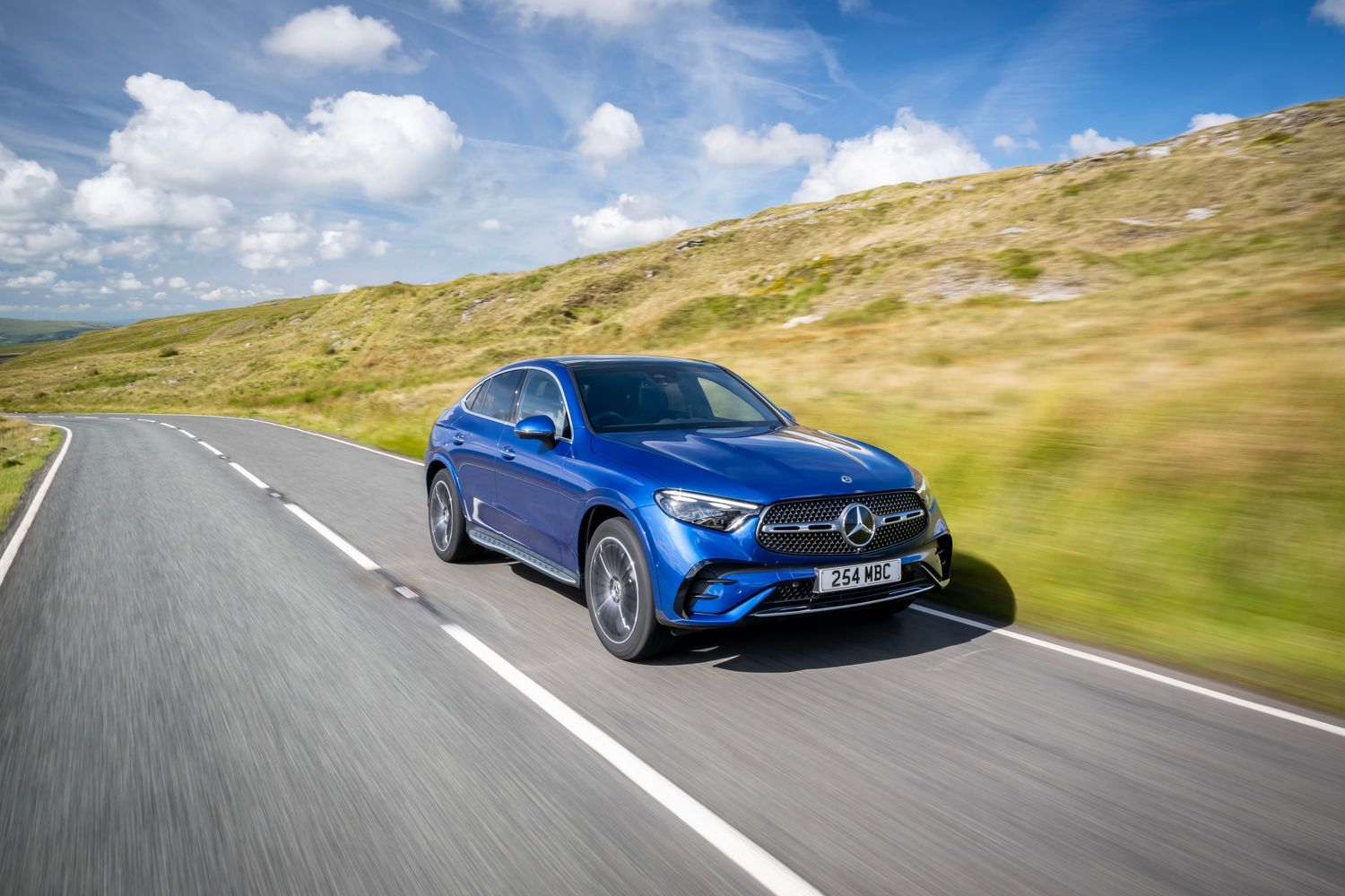The side view of a blue Mercedes-Benz GLC Coupé driving.