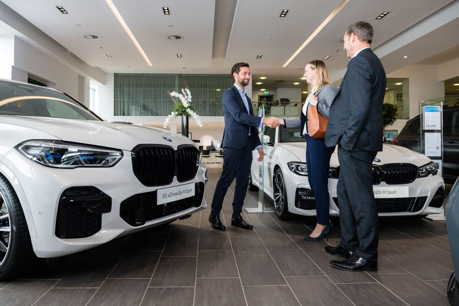 BMW Sales Specialist shakes hands of happy customers who have purchased a new BMW X1 at Bavarian BMW Belfast