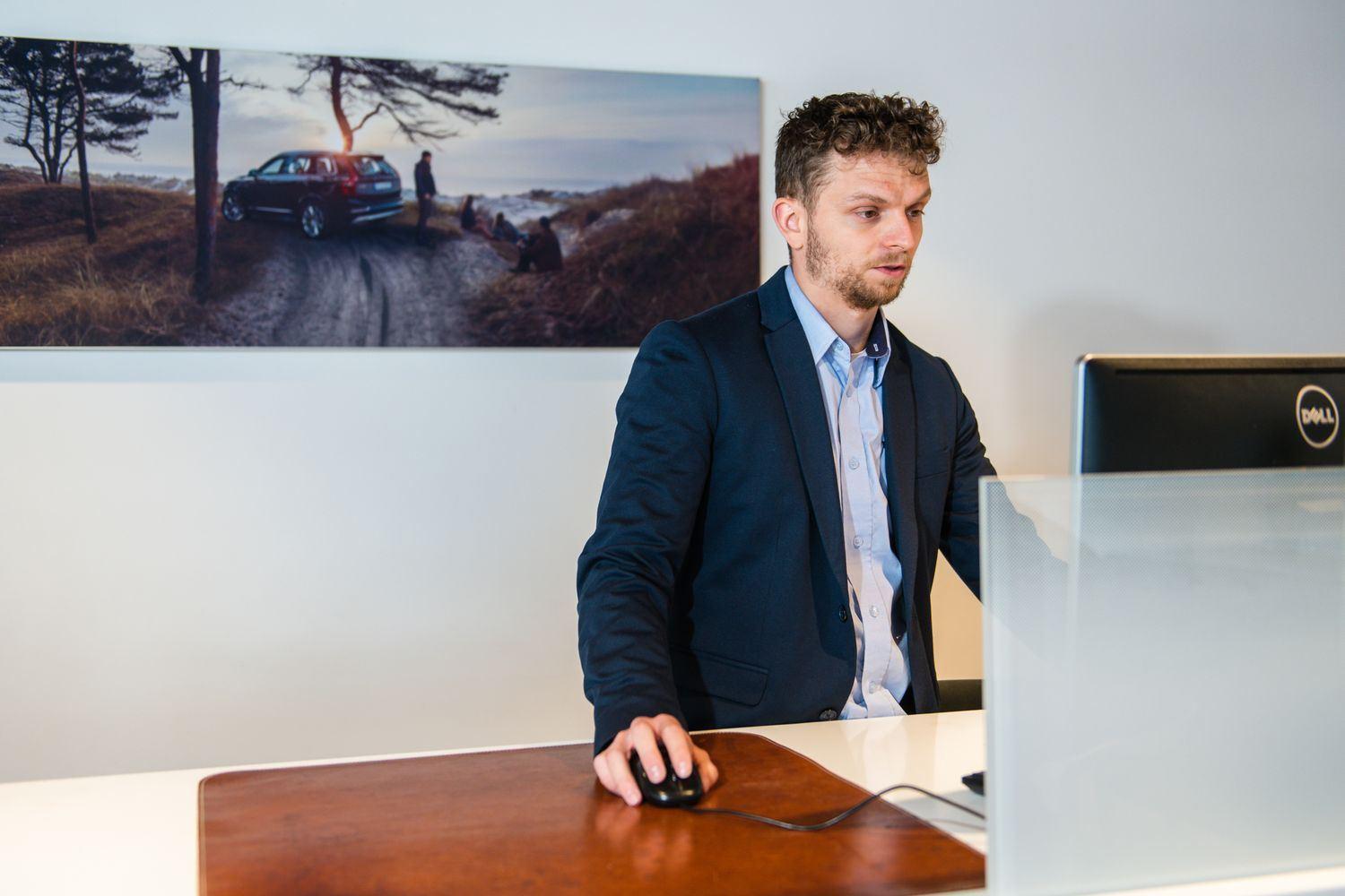 At Agnew Belfast Volvo, a Volvo Servicing Team member helps a customer find out when their MOT is due by searching for the MOT due date on desktop computer.