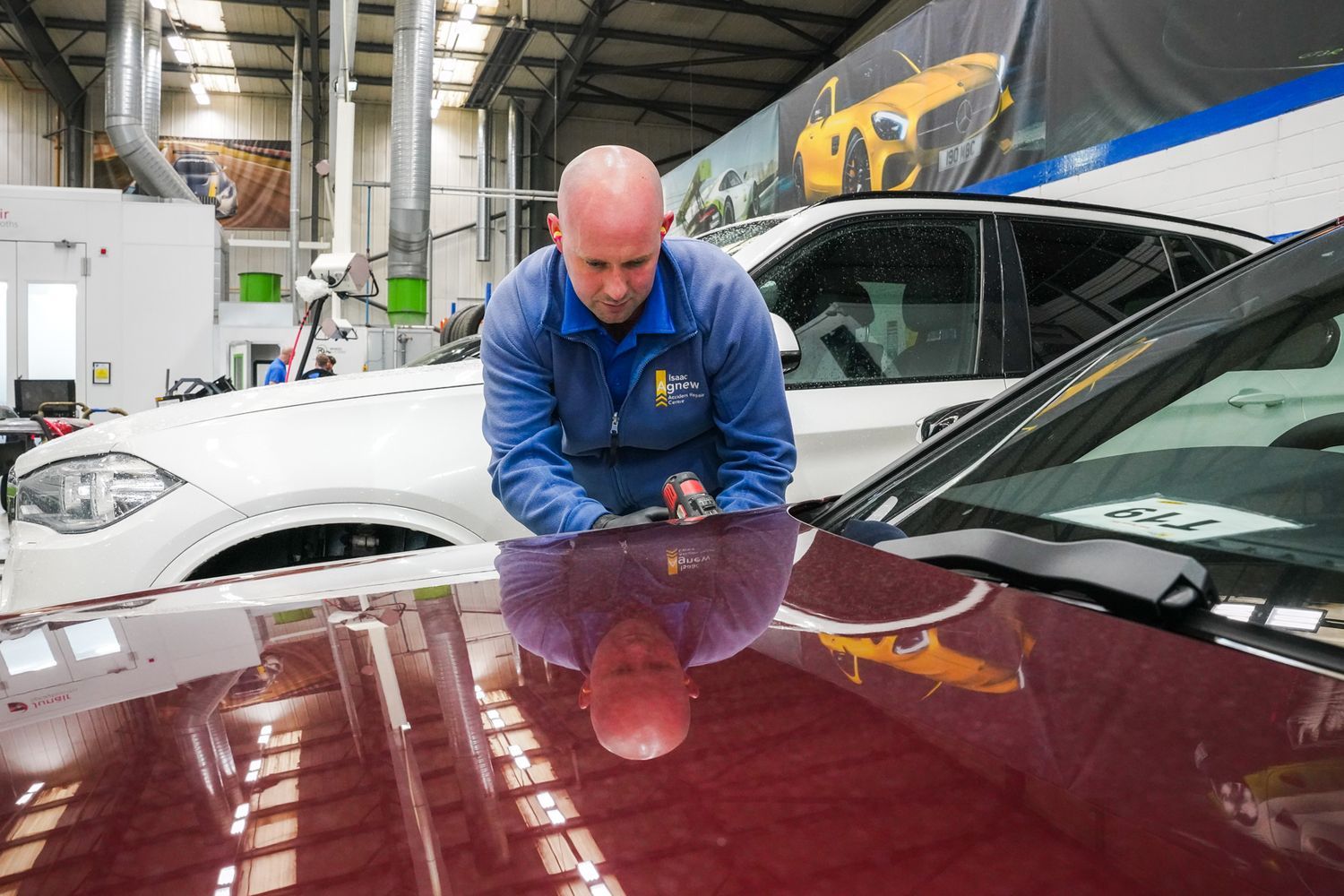Agnew Repair Centre Technician makes small cosmetic repair to the side of a vehicle at Agnew Repair Centre workshop.