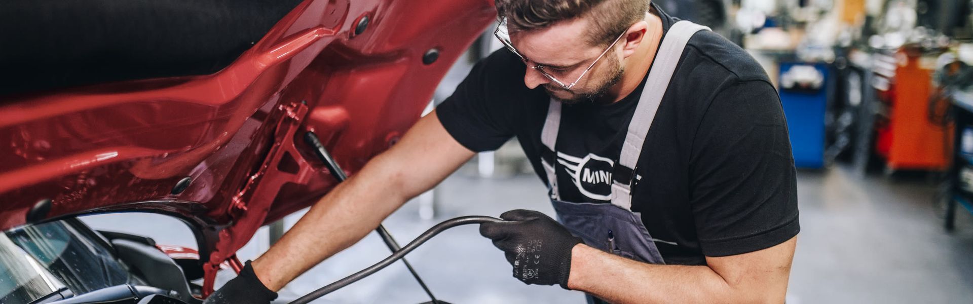 MINI Repair Specialist inspects under the hood of MINI vehicle for routine maintenance at the MINI Repair Centre at Bavarian MINI