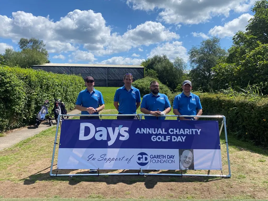 4 Men stood in front of Day's Annual Charity Golf Day banner