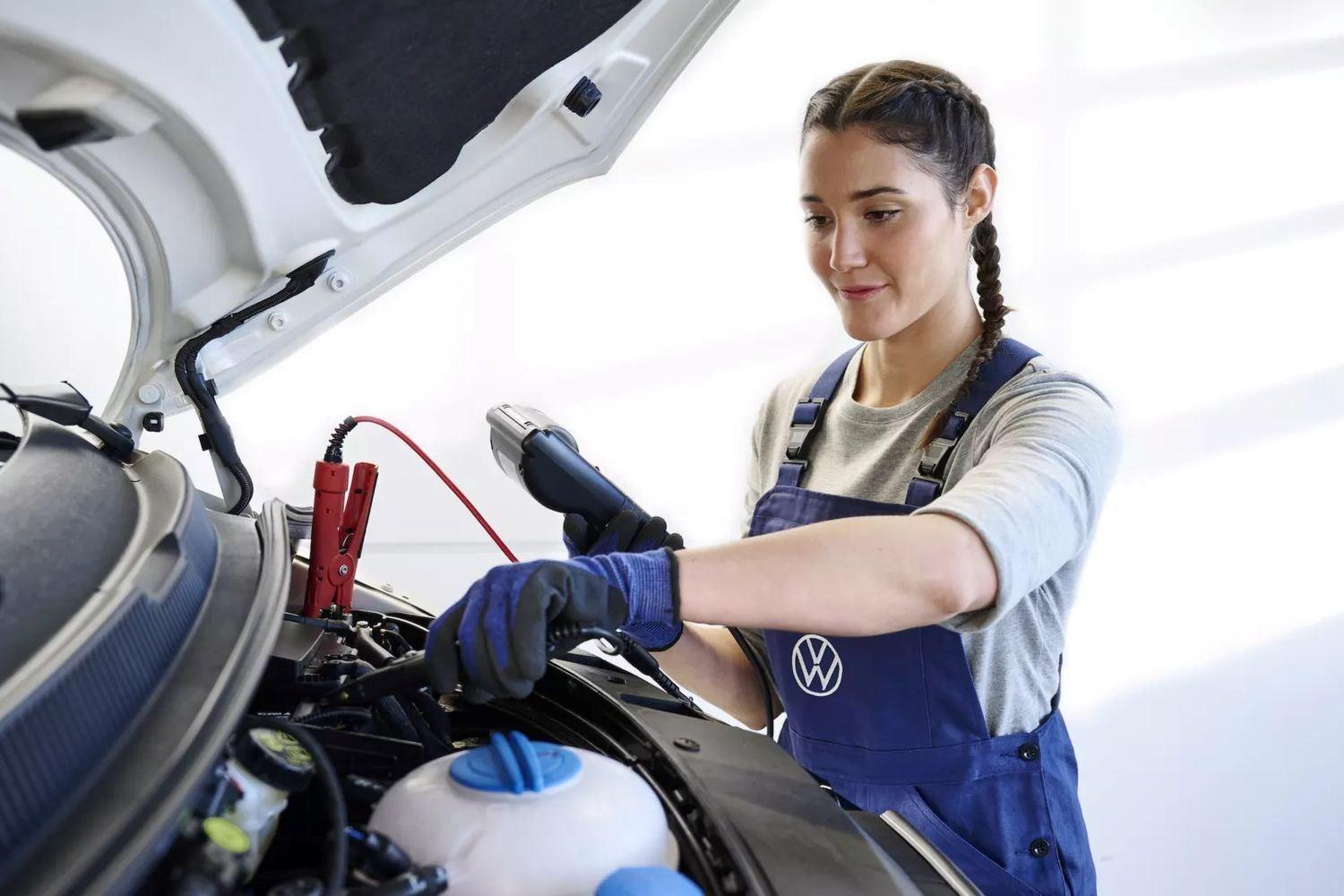 Volkswagen Technician clamps battery while holding a hand-held light during service at Volkswagen Approved Repair Centre at Agnew Van Centre, Mallusk