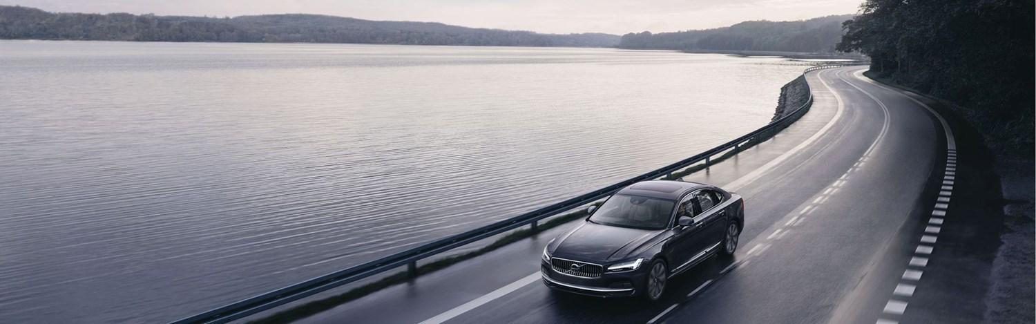 New Volvo S90 drives alongside lake on main carriageway after having roadside assistance