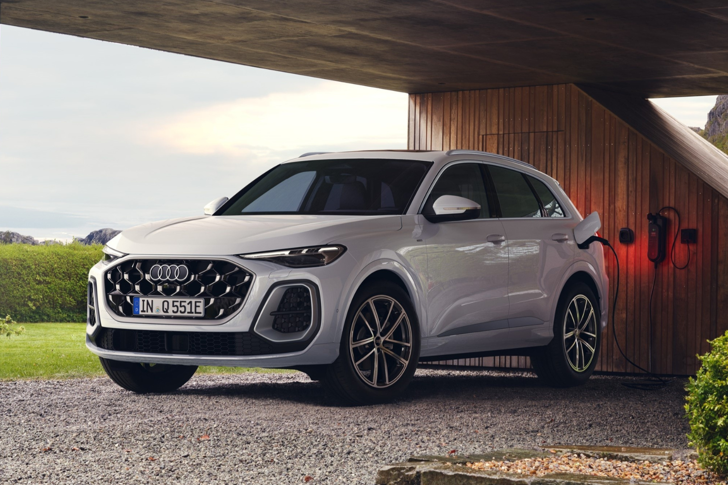 Front view of the new Audi Q5 SUV e-hybrid in Glacier white, charging at an e-charging port.