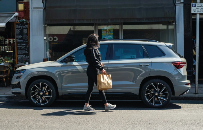 grey skoda karoq parked roadside, person walking in front of vehicle