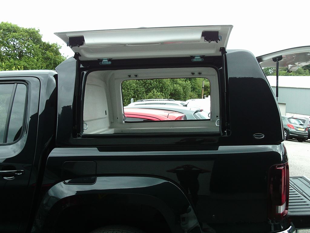Pickup truck canopy with rear window lifted open for access to the load area.