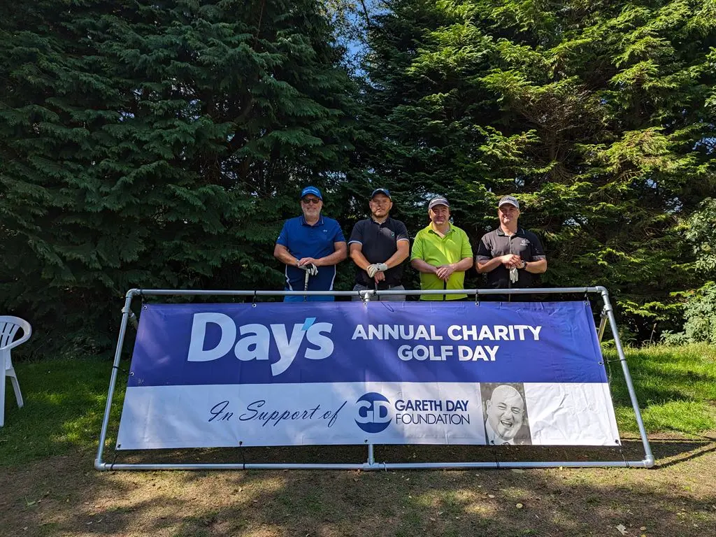4 Men stood in front of Day's Annual Charity Golf Day banner