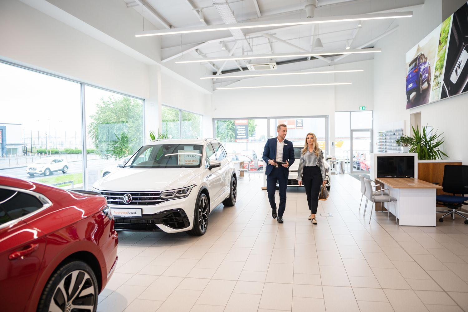 Volkswagen Mallusk Sales Advisor walks with customer through showroom as they discuss the latest Volkswagen new car models