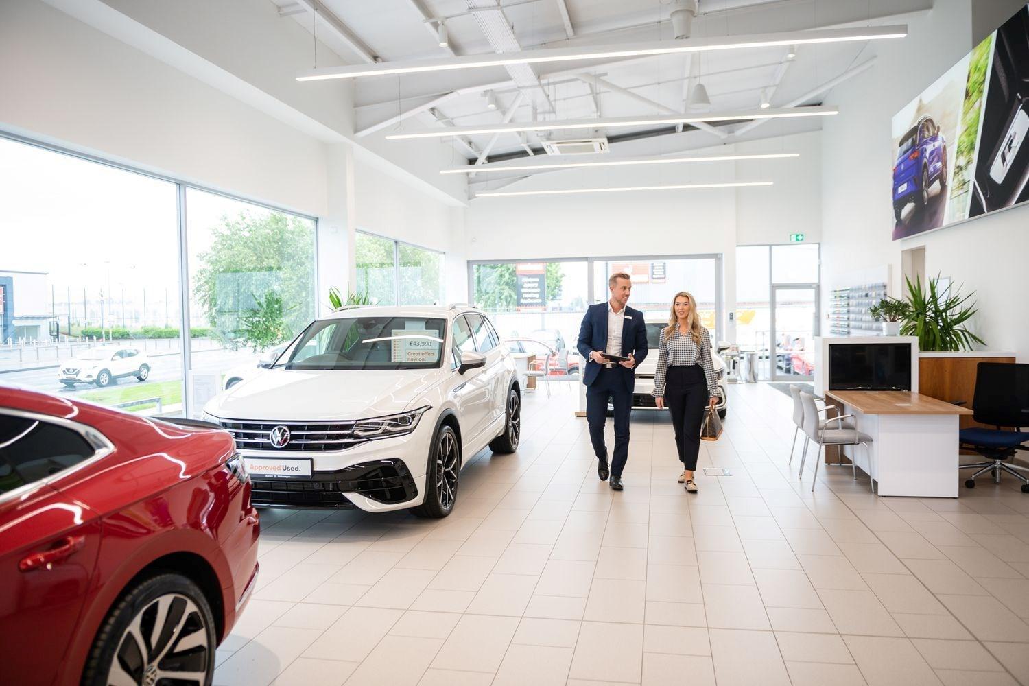 Volkswagen Finance Specialist talks to customer about the different finance packages available for different Volkswagen vehicles as they walk through the showroom at Agnew Volkswagen Mallusk.