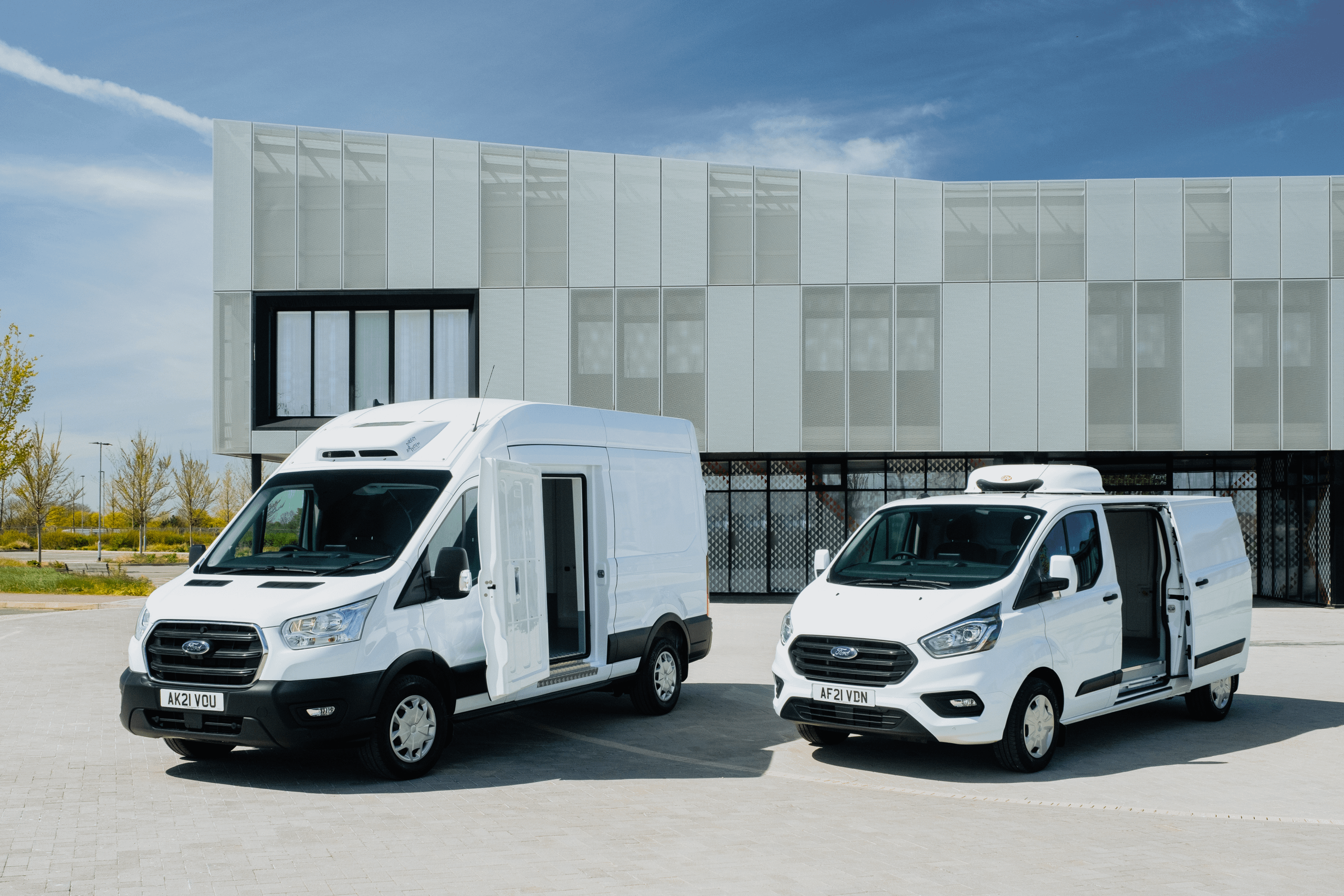 2 Ford vans parked next to each other with side doors open