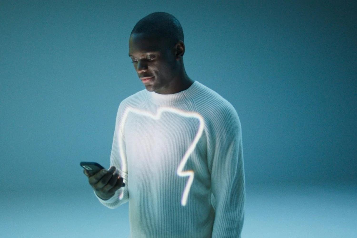 Person on blue background uses the Mercedes me app on mobile phone to connect to their vehicle