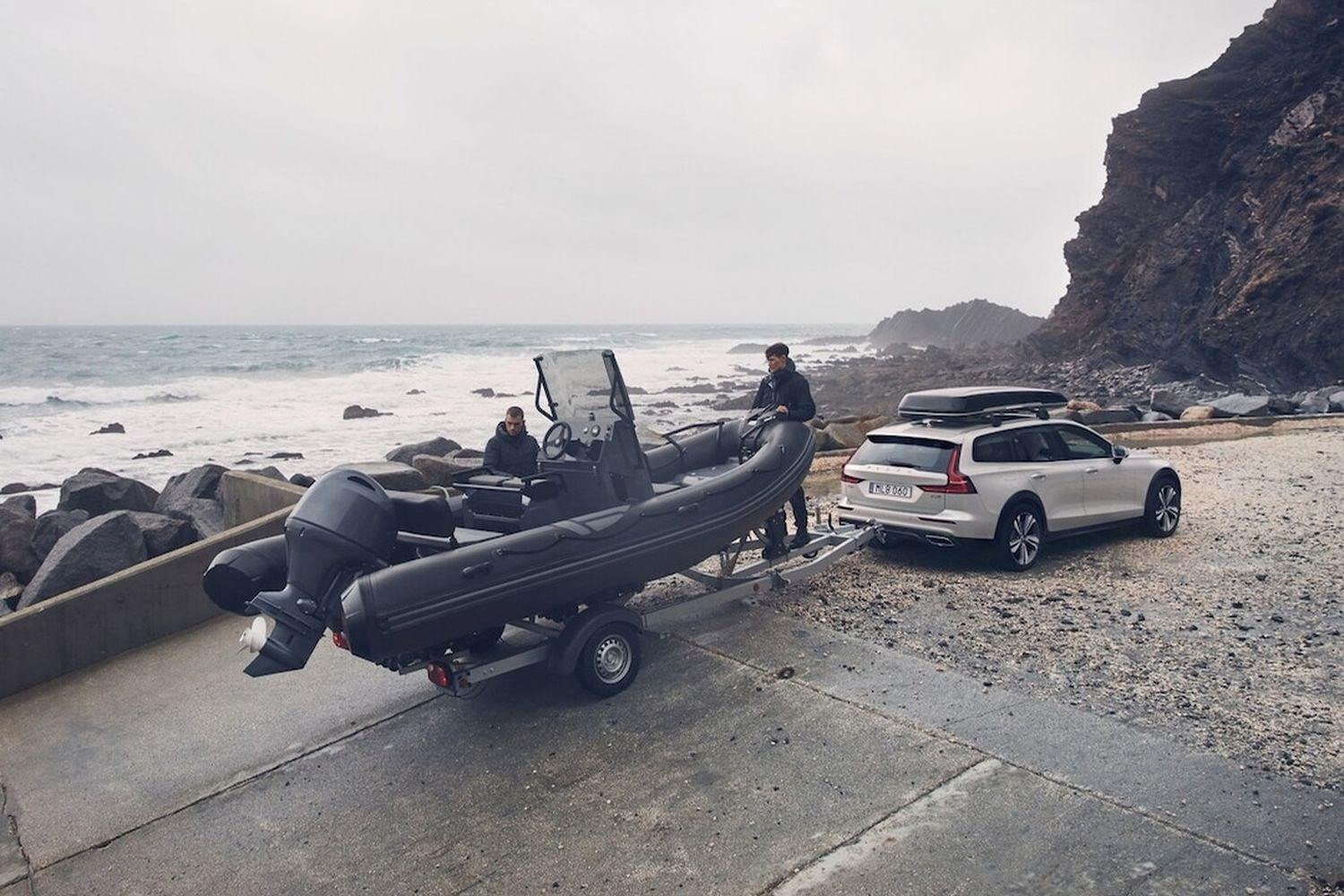 Two people remove boat from tow of Volvo XC90 Recharge with towing bar pack installed.