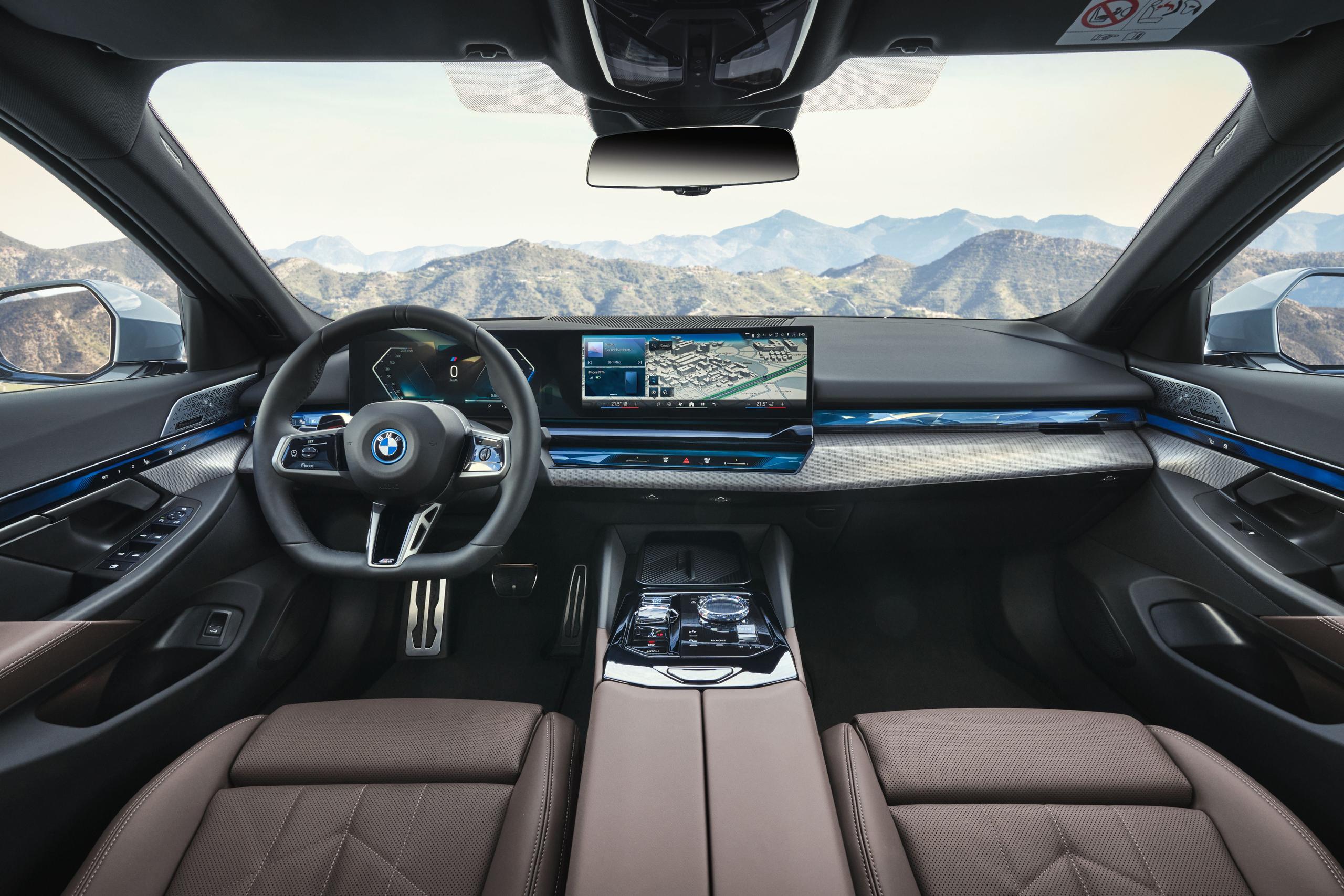 New BMW I5 view of the front driver and passenger seating showcasing its driving controls and infotainment system