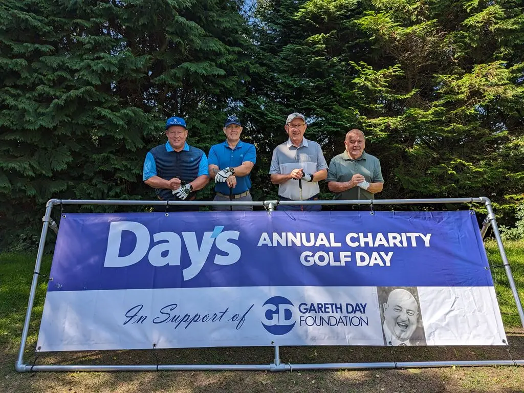 4 Men stood in front of Day's Annual Charity Golf Day banner