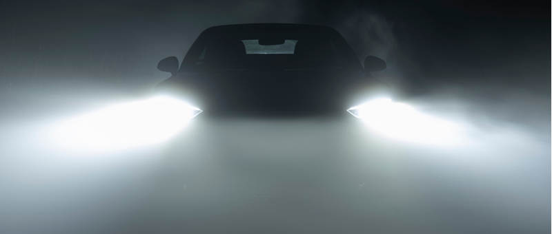 Car in dark foggy area, headlights on