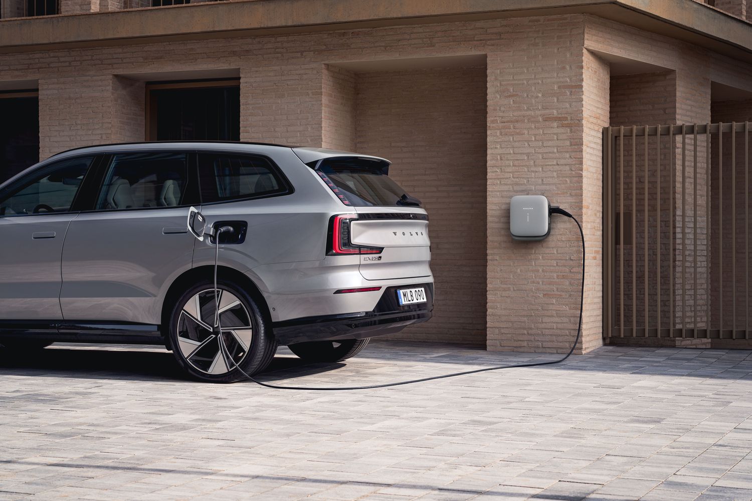 The Volvo EX90, charging with a plug-in home charger.