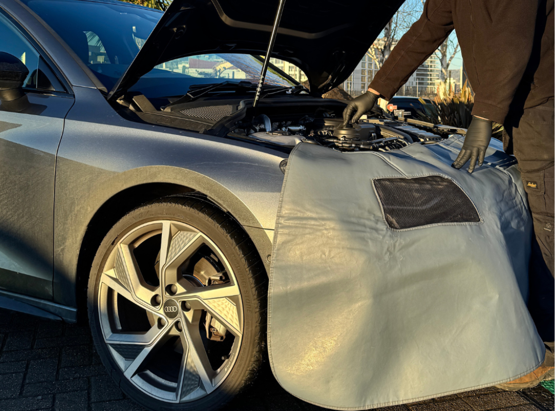 An Audi Mobile support technician performing a service on a customers vehicle.