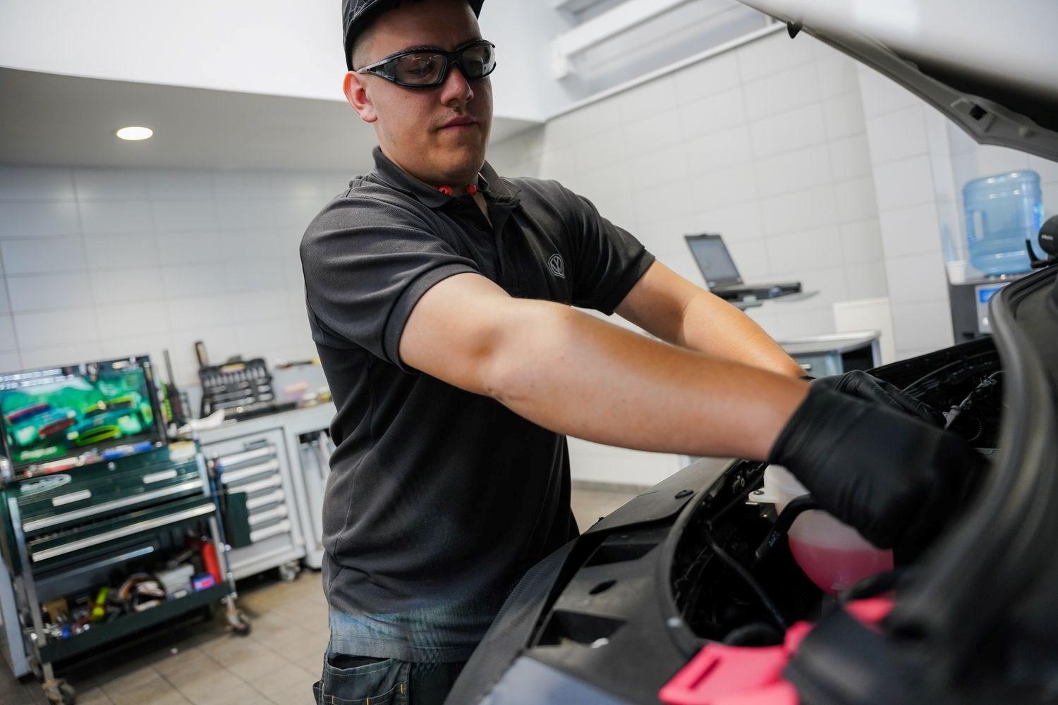 Volkswagen Commercial Vehicle Technician changes coolant on vehicle during maintenance work