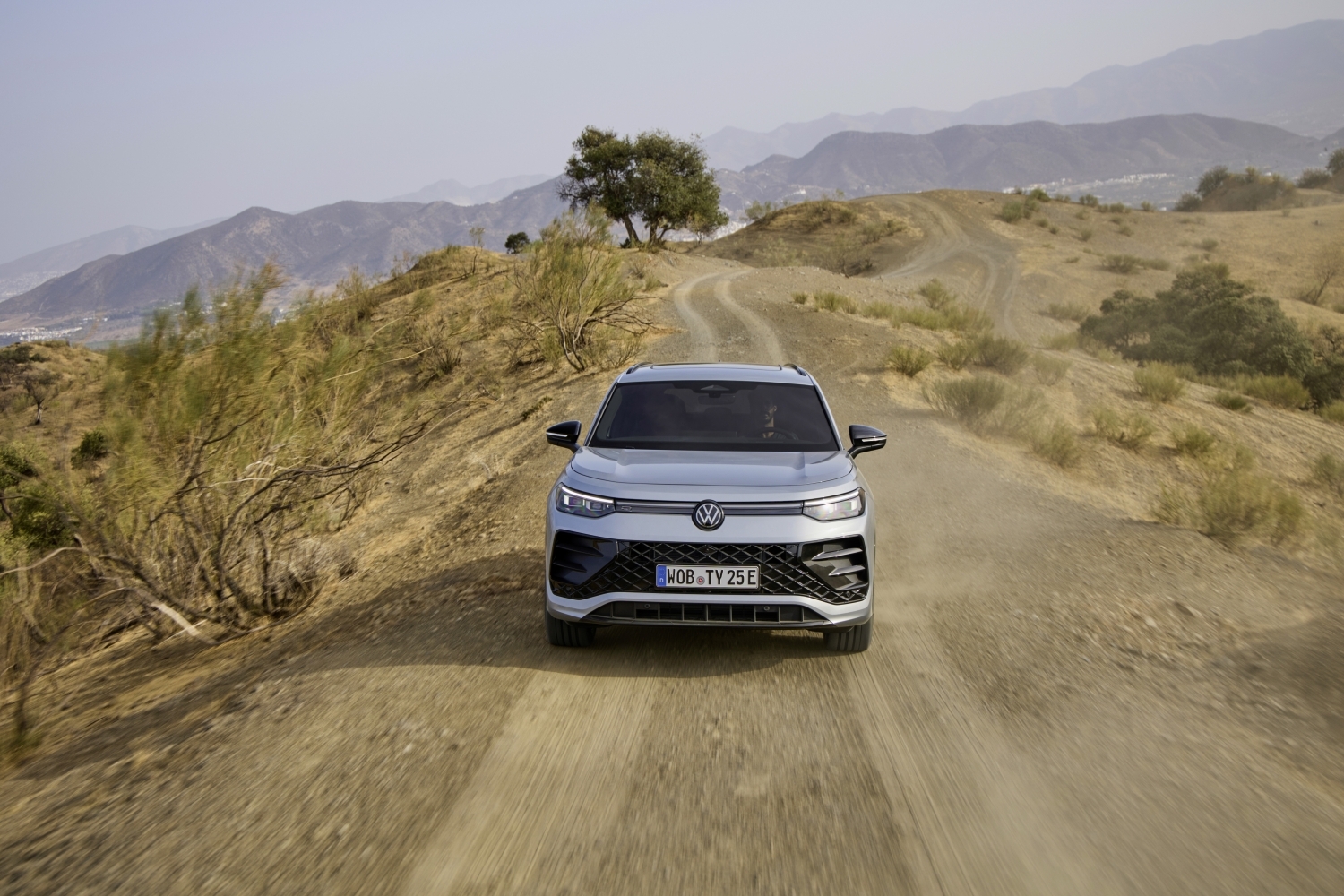 Front view of the new Volkswagen Tayron in Oyster Silver Metallic, driving through the desert.
