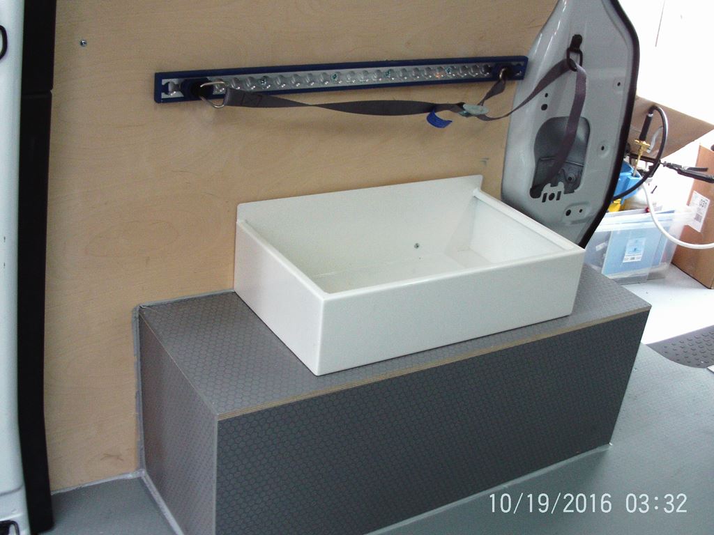 an interior wash station with a fitted basin on a raised platform and wall-mounted rail.