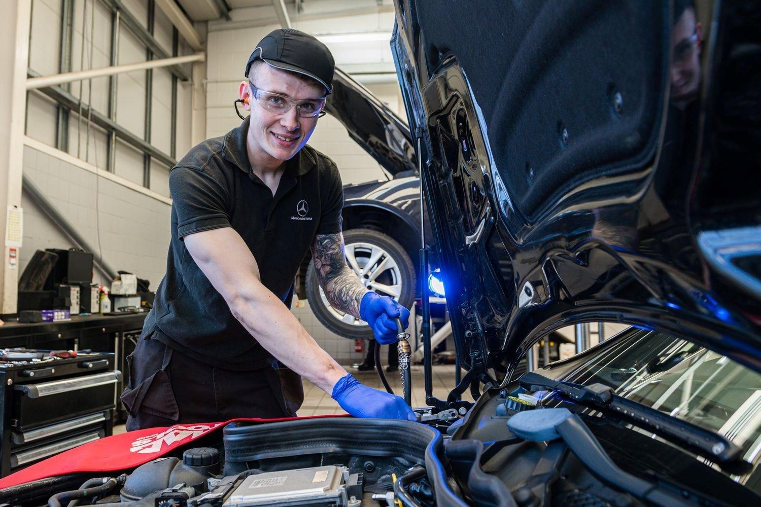 Smiling Mercedes-Benz Technician does under the hood smart repair on Mercedes-Benz vehicle at Mercedes-Benz Repair Centre