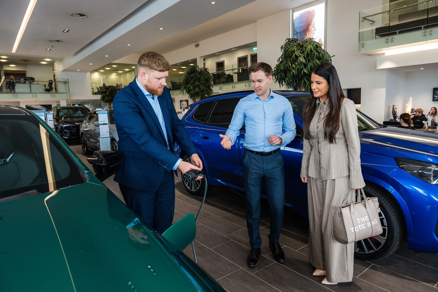 BMW Sales Manager shows customers how to use electric charging port in showroom