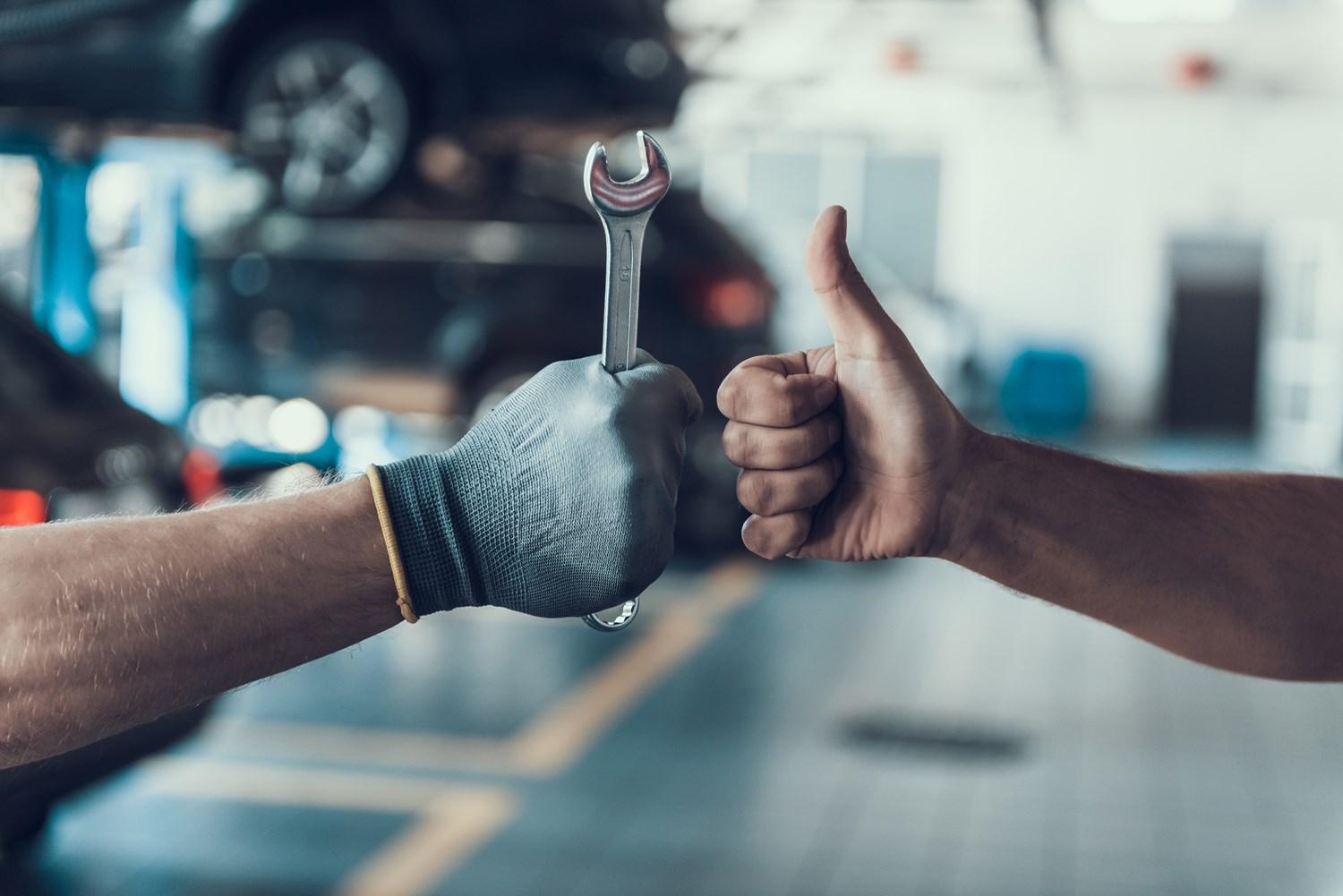 Man holding a wrench and a thumbs up