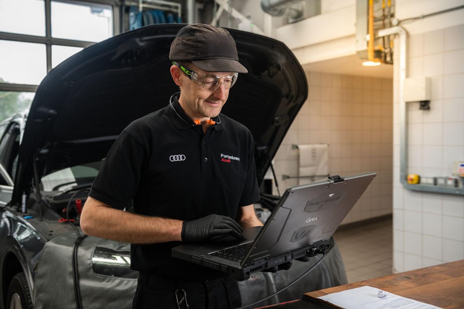 Audi Repair Specialist types notes into laptop during service at Portadown Audi