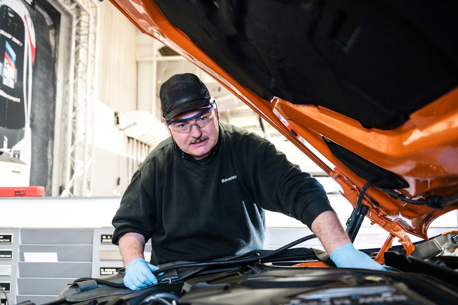BMW Technician makes under the hood repair of orange BMW vehicle at Bavarian BMW Belfast