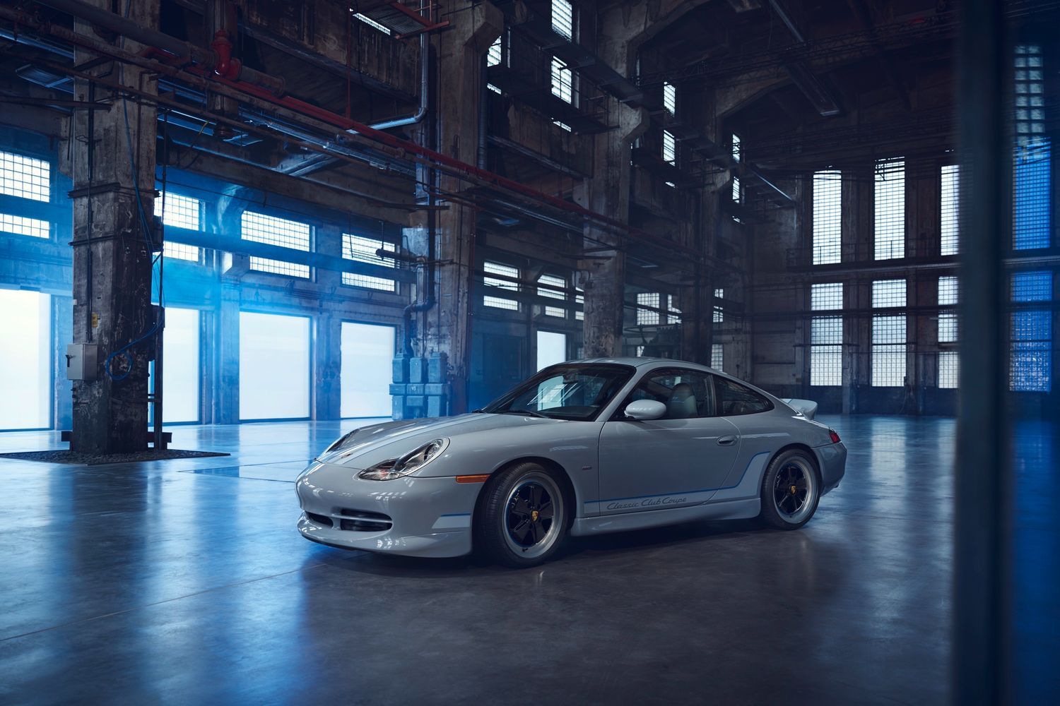 Side view of the all-new Porsche 911 coupe in white, parked in empty warehouse
