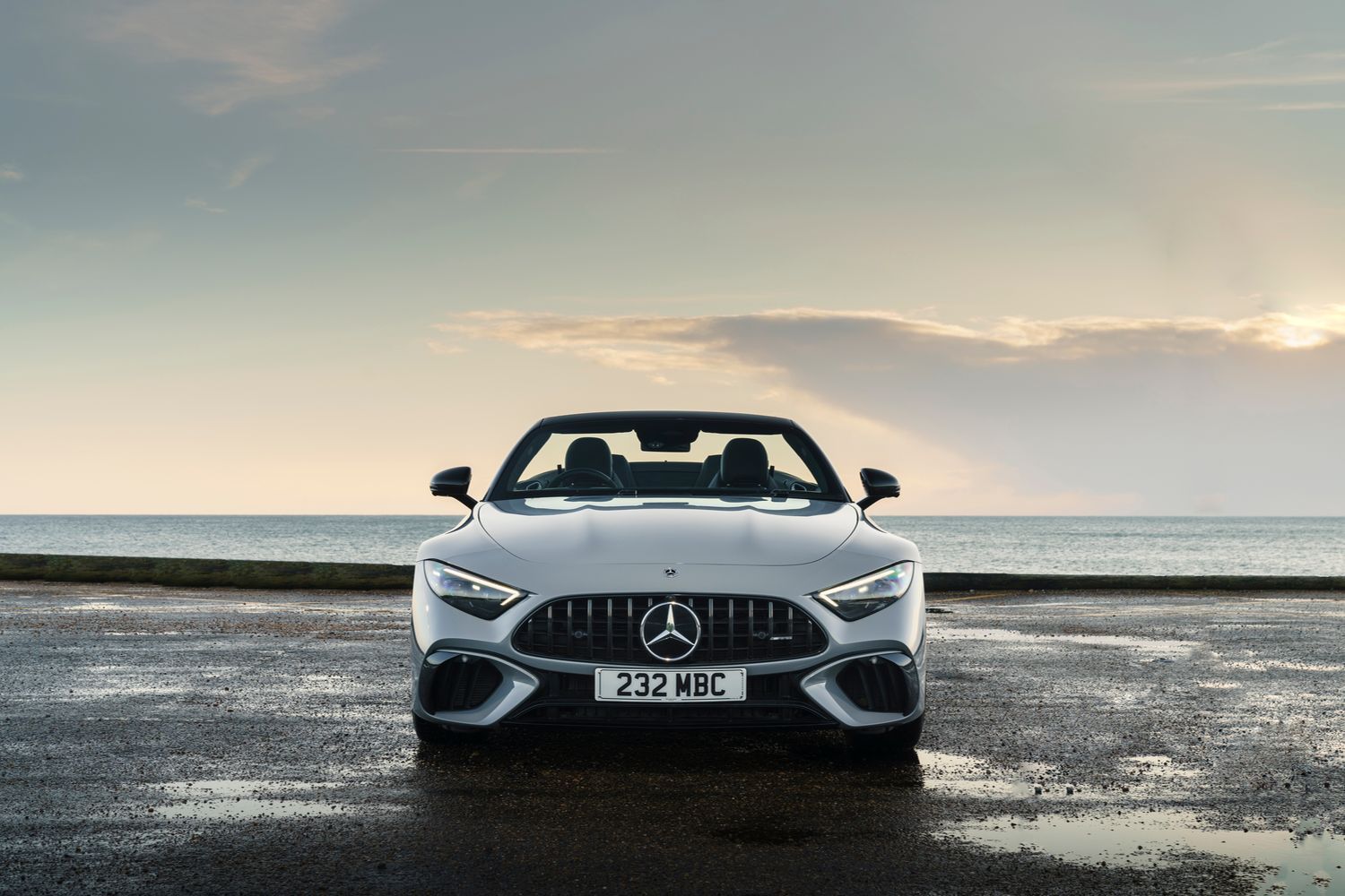 Front view of a white Mercedes-Benz SL parked beside the sea.