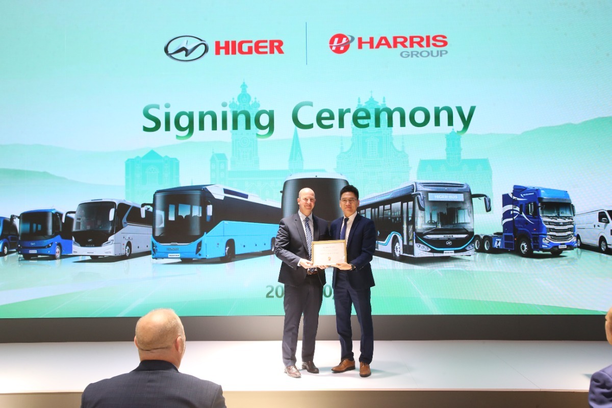 Willie Daniels & Leo Zheng standing together on a stage at the signing ceremony