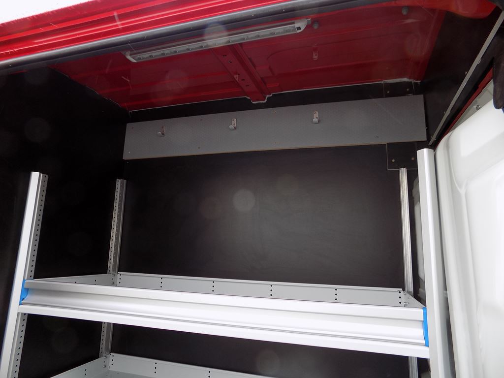 Van interior racking with wall-mounted hooks and overhead storage section.