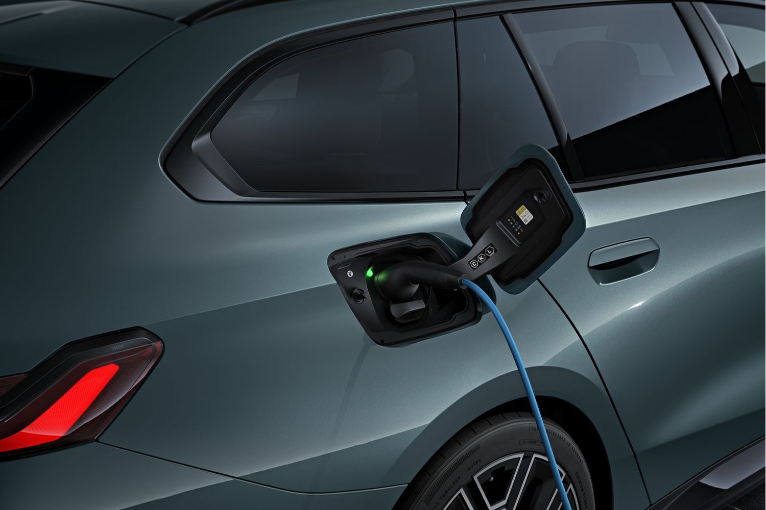 New BMW i5 Touring in green, close-up on electric charging plug
