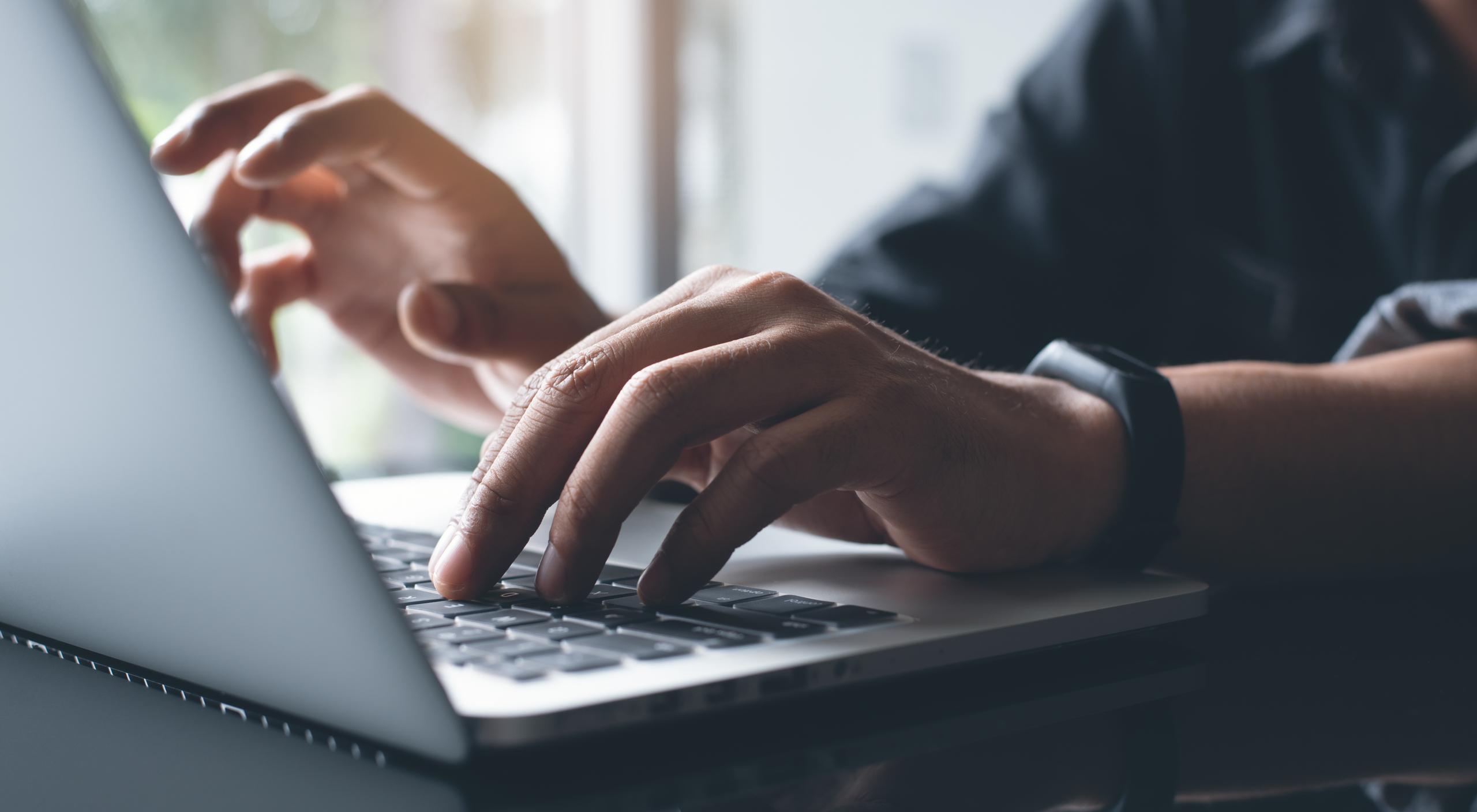 Close-up of a person typing on a laptop, capturing a focused moment of digital work and productivity.