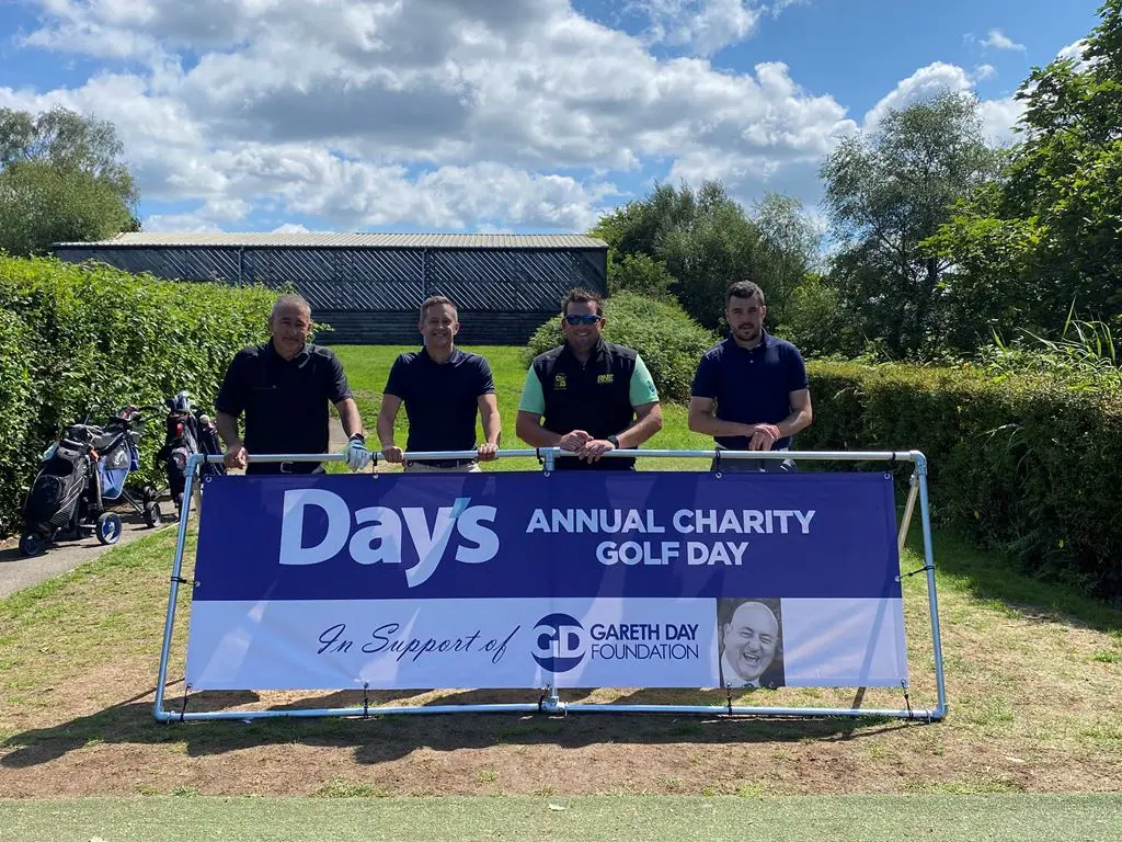 4 Men stood in front of Day's Annual Charity Golf Day banner