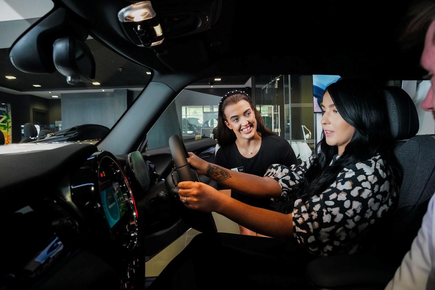 MINI Sales Specialist speaks to customers about the key features of the MINI Countryman interior as they sit inside of the vehicle at the Bavarian MINI Showroom