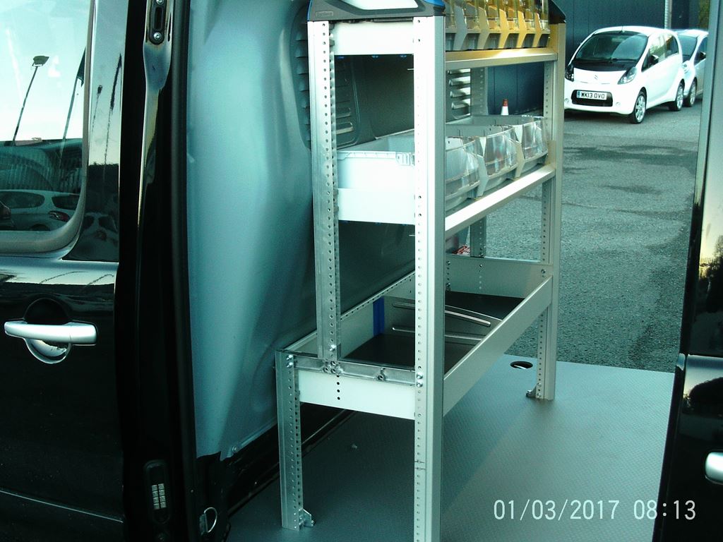 Side door view of a fitted work van with metal shelving, trays and small parts bins.