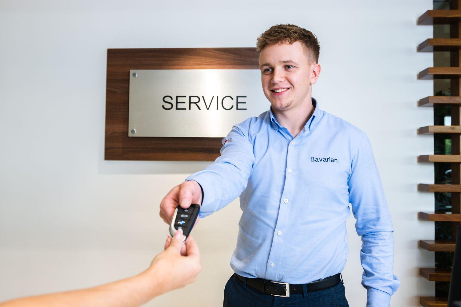Bavarian Service Specialist hands over keys to customer at the Bavarian BMW Service area after successful service