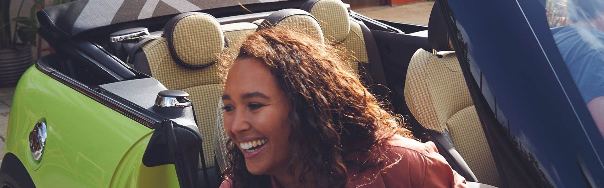 Smiling person gets out of light green MINI Cooper with personalised styling and trim