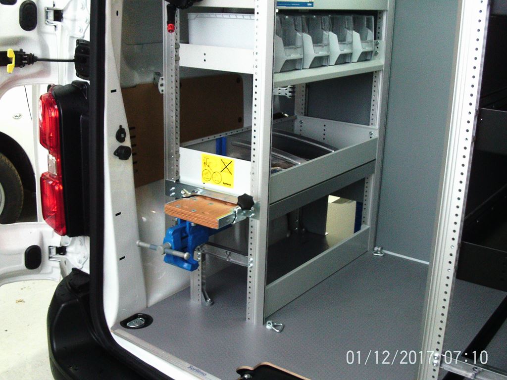 Van side access showing racking system with organiser bins and mounted bench vice.