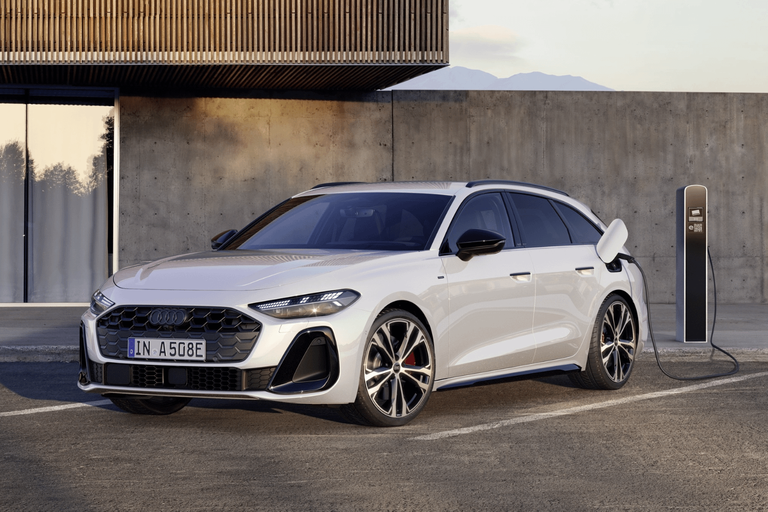 2025 Audi A5 Avant e-hybrid in Glacier White charging at a charging port.