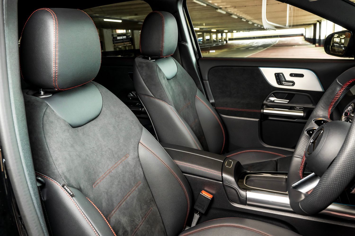 Mercedes-Benz EQA interior dark seats and steering wheel with red stitching.