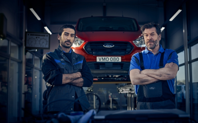 2 car mechanics stood in front of raised red Ford Transit