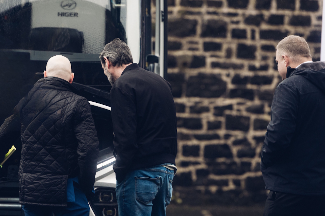 people talking in front of a parked bus